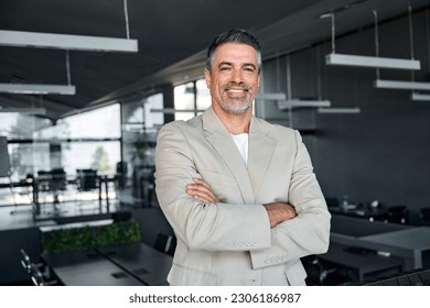 Smiling confident middle aged business man, mature older professional successful company ceo corporate leader wearing beige suit standing in modern office arms crossed looking at camera, portrait. Foto stock