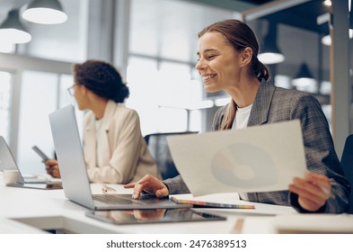 Smiling female accountant working with financial statement and use laptop while sitting in office  Adlı Stok Fotoğraf
