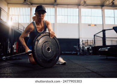 체육관에서 근력 운동을 하는 동안 바벨에서 웨이트 플레이트를 조정 하는 여자 스포츠 선수. 스톡 사진
