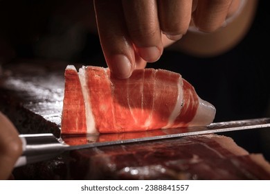 Spanish acorn-fed Iberian ham. Iberian ham cutter hand cutting slice for tasting. Typical high quality slice of Iberian ham with its veins and fat. – Ảnh có sẵn