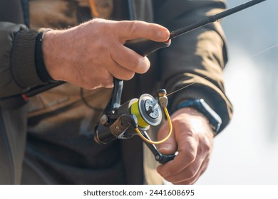 川で釣りを回転させると、漁師は釣り竿を手に持ってリールを回します。の写真素材