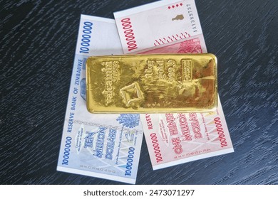 Stockholm, Sweden - May 15, 2024: One hundred million dollars and ten million dollars banknotes of Zimbabwe with gold bullion bar. Zimbabwe's new gold-backed currency - the ZiG, or Zimbabwe Gold conce 编辑库存照片