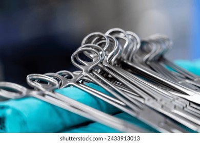 Sterile surgical instruments and tools including scalpels, scissors, forceps and tweezers arranged on a table for a surgery, Sterilized surgical instruments on the blue wrap	 Arkistovalokuva