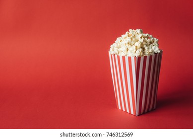 Striped box with popcorn on red background Stock Photo
