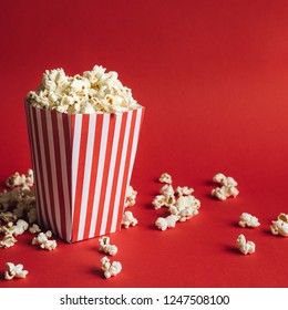 Striped box with popcorn on red background. Square format Stock Photo