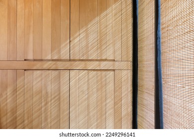 the striped light and shadow on wooden wall from bamboo blind curtain. sun protection curtain of window frame for house decoration. Arkistovalokuva