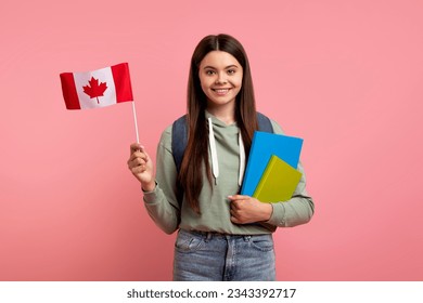 Study Abroad. Beautiful Teen Girl Holding Flag Of Canada And Workbooks, Smiling Feemale Teenager With Backpack Enjoying Student Exchange Programs And Language Schools, Standing On Pink Background Adlı Stok Fotoğraf