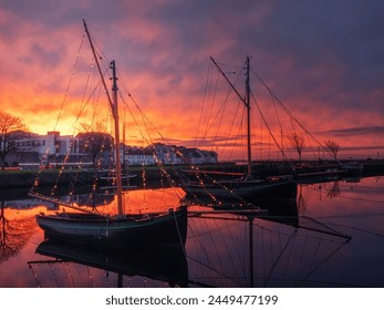 Stunning sunset scene over city buildings with reflection in water. Claddagh, docks area, Galway city, Ireland. Rich saturated colors. City center landmark area. Wooden boats in dock., fotografie de stoc