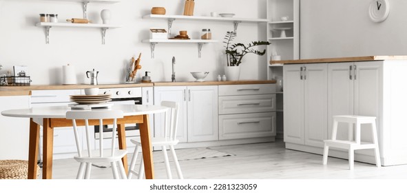Stylish interior of light kitchen with dining table 库存照片