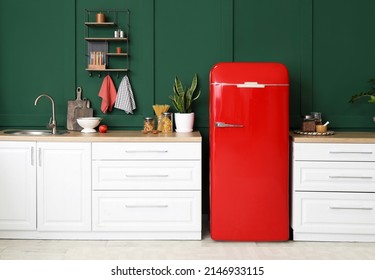 Stylish refrigerator and counters near green wall in kitchen Stock Photo