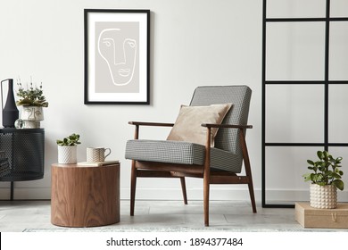 Stylish scandinavian composition of living room with design armchair, black mock up poster frame, commode, wooden stool, book, decoration, loft wall and personal accessories in modern home decor. Stock Photo
