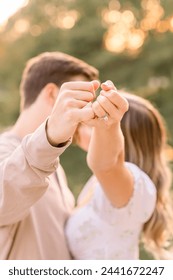 婚約指輪を見せびらかすピンキーの約束をして、婚約中のカップルとの夕日のキス。 の写真素材