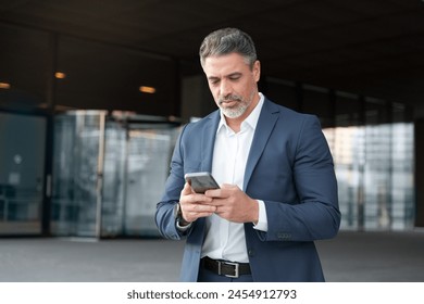Successful mid age senior businessman holding mobile phone. Portrait of focused executive ceo manager. Latin adult man in suit using smartphone application app device for business at office outdoors Foto stock