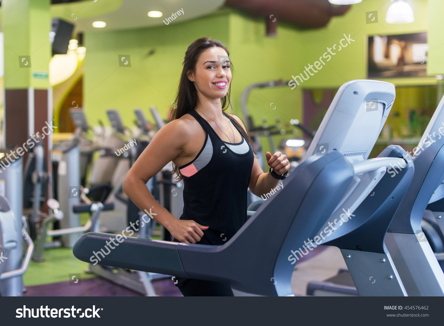 Fit women doing cardio exercises, running on treadmills in the gym