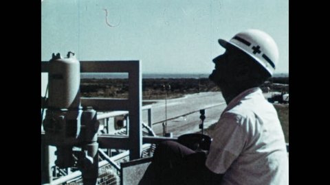 1960s: UNITED STATES: Saturn flight testing. Rocket takes off from gantry. Men in mission control. Cape Canaveral visit. Astronaut with cup: redactionele stockvideo
