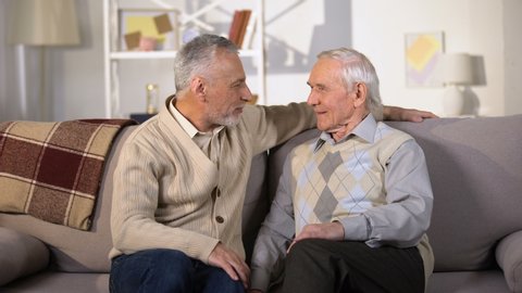 Elderly male friends laughing and hugging at home, true old friendship, rest Stock-video