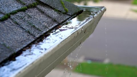Roof gutters clogged with leaves and overflowing water slow motionの動画素材