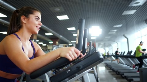 A beautiful athletic young brunette woman in sportswear in the gym is engaged on a bike. Healthy lifestyle. Vídeo Stock