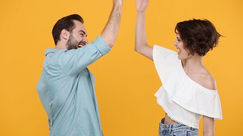 Young fun couple friends bearded guy girl 20s in casual clothes posing isolated on yellow background studio. People emotions lifestyle concept Meeting together greeting giving high five clapping handsの動画素材