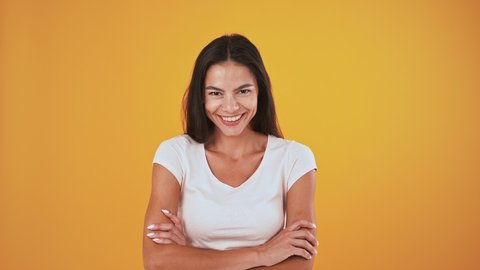 Female is laughing while posing against orange studio background Video de stock