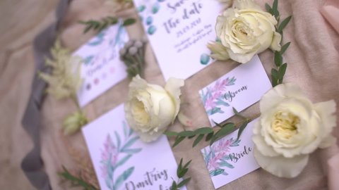 Wedding invitation cards with watercolor drawings, flowers and twigs lie on pastel fabric Video Stok