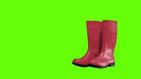 Rubber boots of red color on a green background: stockvideo