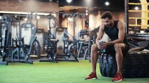 sportsman listening music and drinking water in gym Stock Video