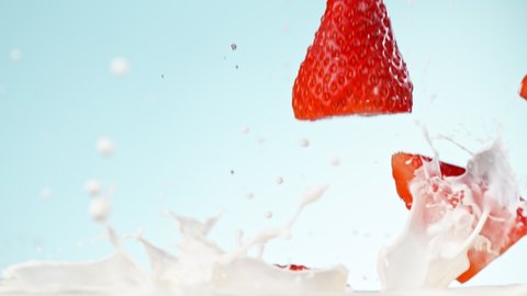 Super slow motion of strawberries falling into cream., videoclip de stoc