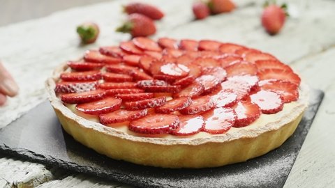 The confectioner serves delicious strawberry tart on the table. 库存视频