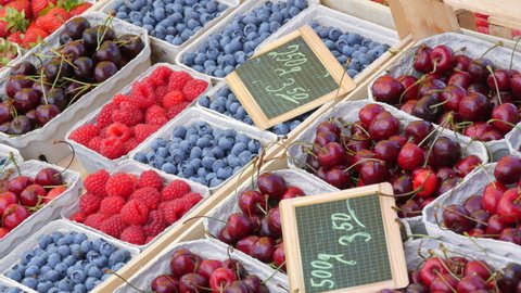 Kehl, Germany - May 17, 2022: Lots of summer berries on market counter in cardboard eco boxes. Blueberries, raspberries, cherries, sweet cherries, strawberries for sale on street with price tags. 에디토리얼 스톡 비디오