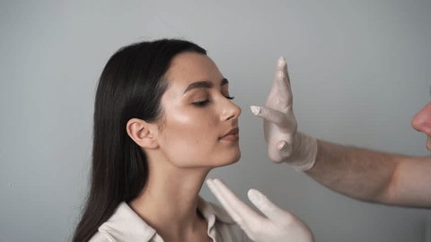 4k video ENT doctor is touching nose and consulting girl patient before septoplasty surgery. Rhinoplasty is reshaping nose surgery for change appearance of the nose and improve breathing.の動画素材