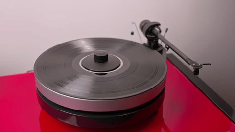 View of person's hands as they turn on high-fidelity vinyl record player and lower tonearm onto vinyl to start listening to music. Arkivvideo