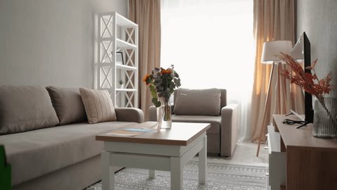 A beautiful bouquet of flowers stands on a table in a beautiful new apartment with a table, a window and a bed, a beautiful designer room interior స్టాక్ వీడియో