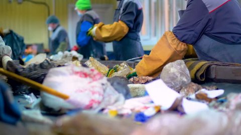 Workers at conveyor sorting garbage at a recycling plant.の動画素材