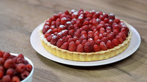 Woman's hand cut with a kitchen knife tart with raspberries 库存视频