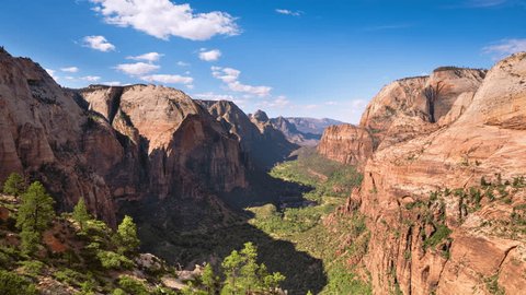 Timelapse of a lush valley in between tall mountains made of layers of red rocks from the summit of Angel’s Landing. Zion National Park, Utah, USA Video Stok