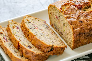 A sliced loaf of zucchini bread with dried cranberries