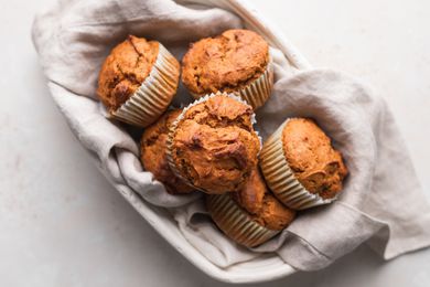 Classic pumpkin muffins nestled in a cream colored linen and oval bowl.