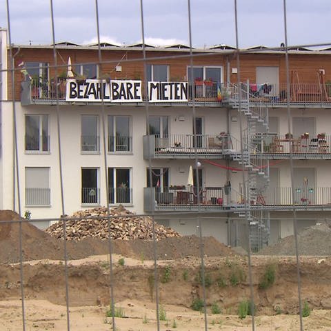 Ein Haus mit einem Banner mit der Aufschrift: "Bezahlbare Mieten". Die Sozialquote für Wohnungsmieten ist Thema im Mannheimer Gemeinderat
