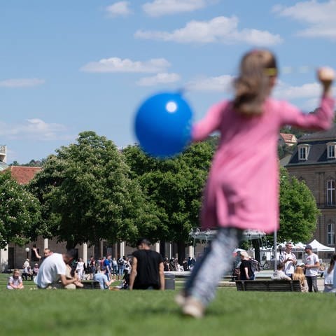Ein Kind spielt auf dem Stuttgarter Schlossplatz mit einem Luftballon.