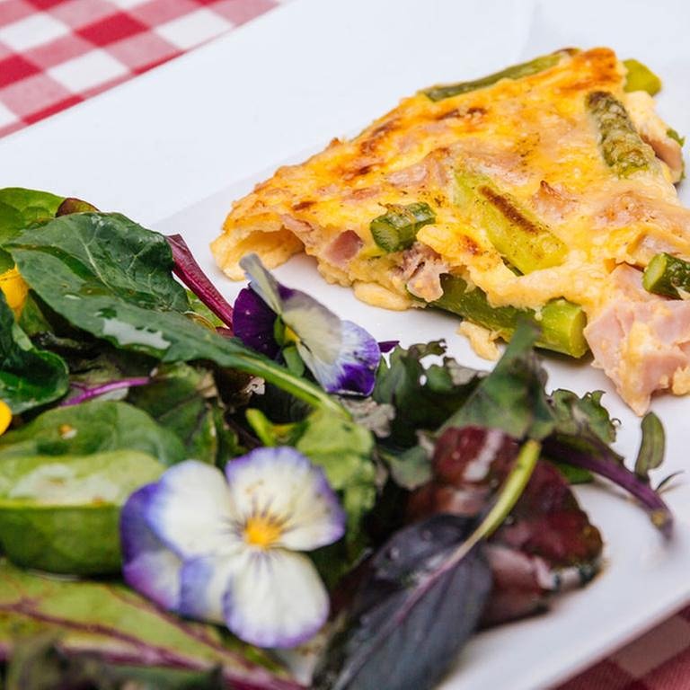 Parmesan-Omelett mit Spargel, Schinken und Wildkräutersalat mit Blüten dekoriert