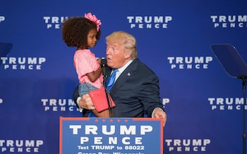 Republican presidential nominee Donald Trump holds a child as he speaks during a rally