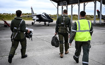 Ukrainian trainees and a French military instructor walk towards an Alpha Jet fighter  ahead of a flight, at a French Army air base in south-western France