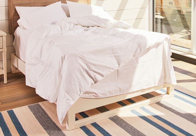 The Brooklinen Down Alternative comforter on a bed in a brightly lit bedroom