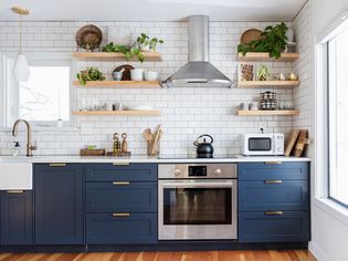 Modern kitchen with blue lower cabinets and open shelving.