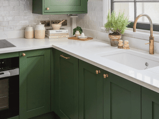 green kitchen cabinets and white countertops with brass hardware
