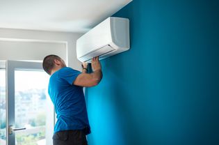 Person installing a new air conditioner in a home