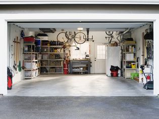 Clean car garage with shelves, tools, and bikes.