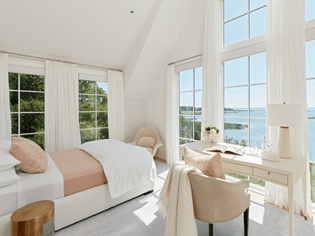 A room facing an ocean view is filled with whites and creams and soft materials.