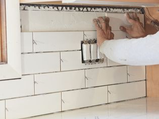 White tile backsplash being installed for kitchen remodeling